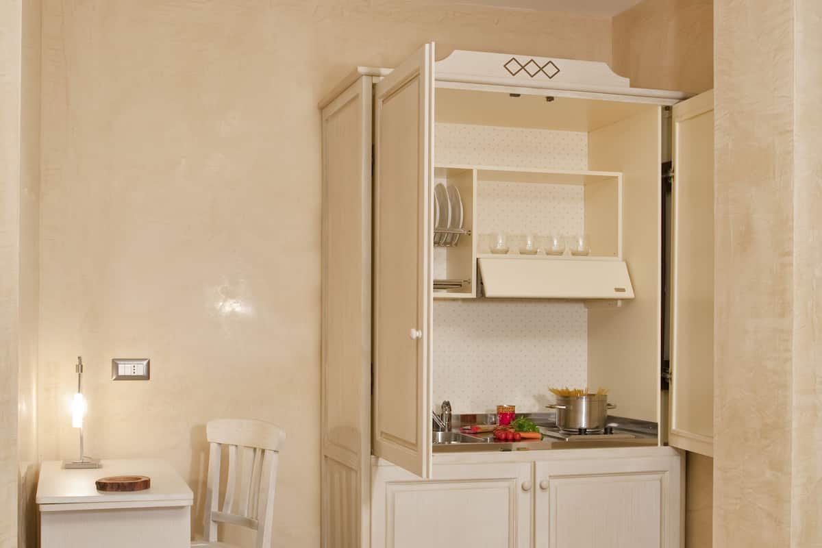 A compact kitchen with a white countertop, a chair, and a cabinet with a built-in oven.
