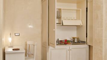 Una cocina pequeña con cubierta blanca, una silla y un armario con horno integrado.