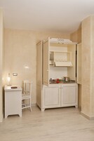 Una cocina pequeña con cubierta blanca, una silla y un armario con horno integrado.