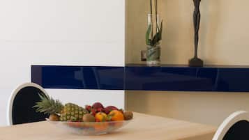 Una mesa de comedor con un frutero, un florero con flores blancas y una escultura.