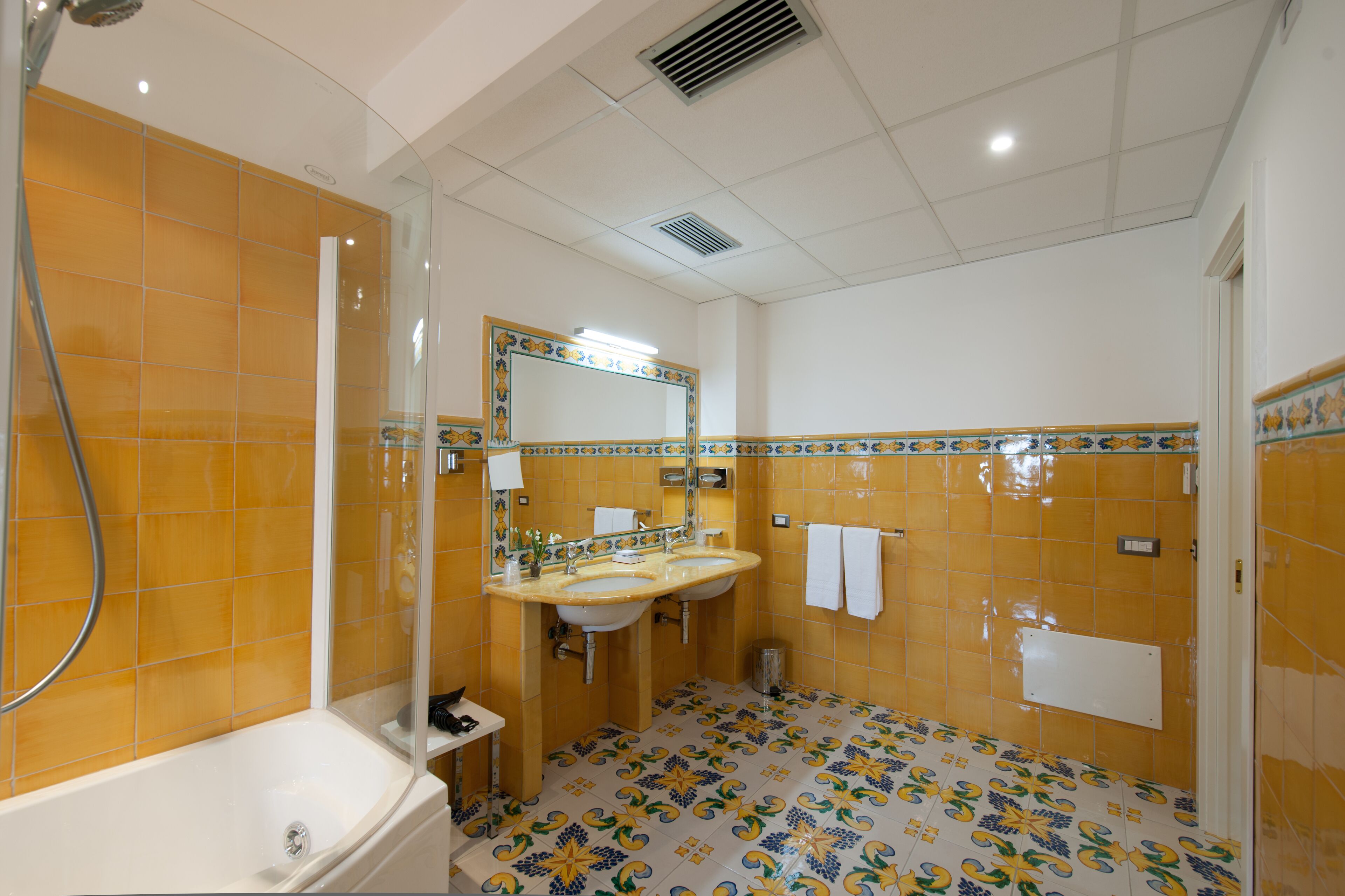 Un baño con bañera, dos lavamanos, un espejo y ducha.