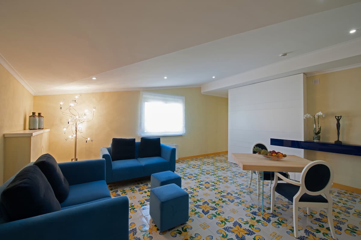 A modern living room with a blue sofa set, a small table with fruit, and a decorative floor lamp.