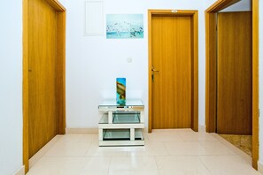 Ein Flur mit Holztüren, einem Glastisch mit einer Vase und einem gerahmten Bild an der Wand.