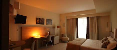A hotel room with a bed, a desk, a chair, and a television.