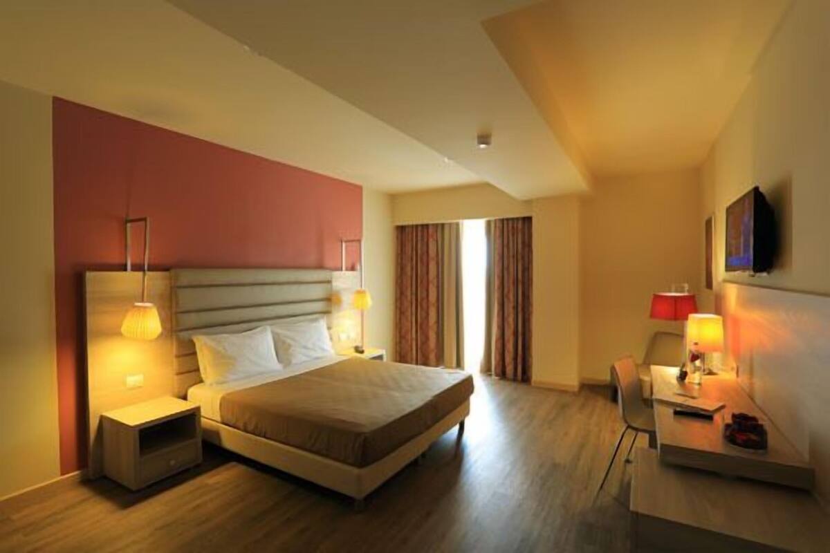 Una habitación de hotel con cama, mesitas de noche, escritorio y televisor.