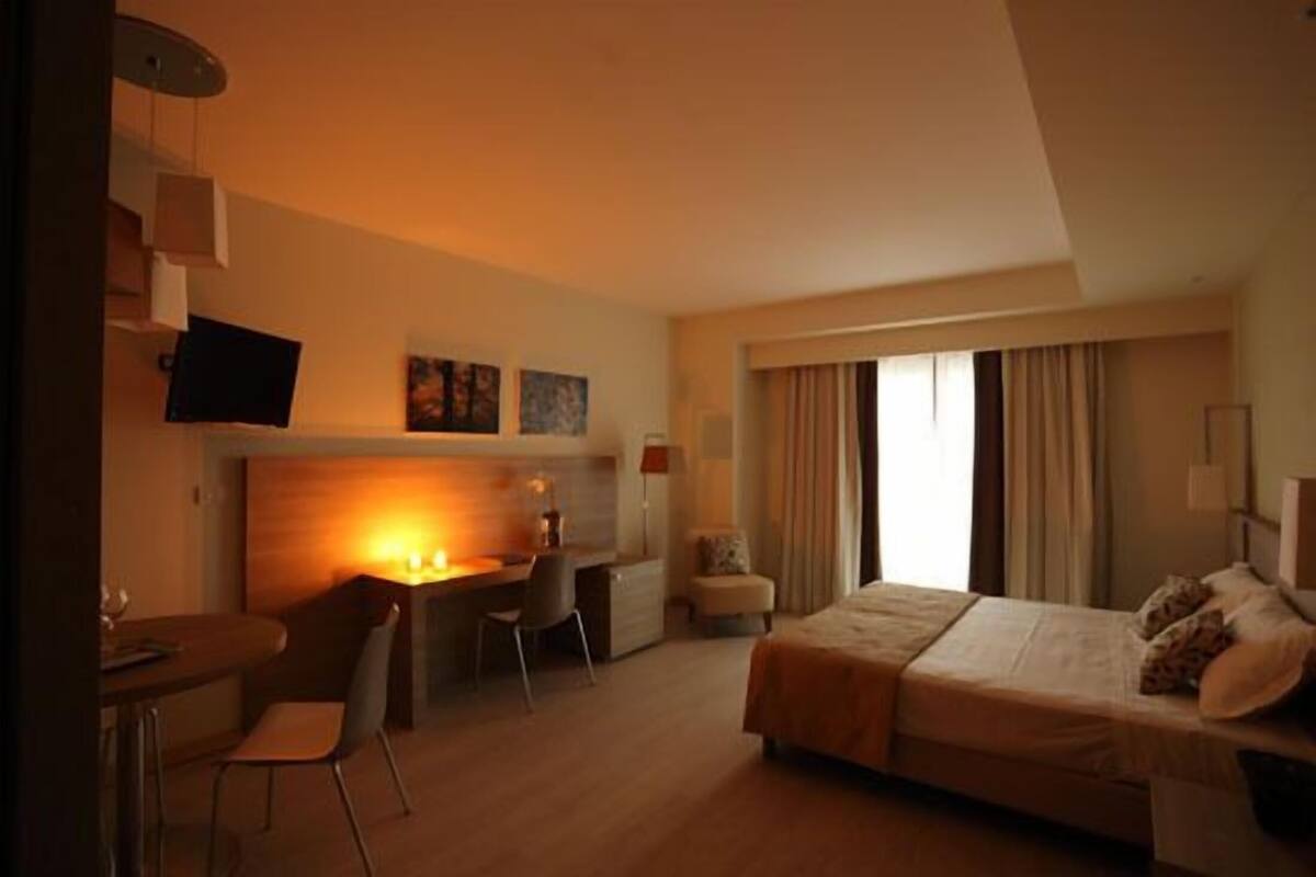 Habitación de hotel con cama, escritorio, silla y televisor montado en la pared.