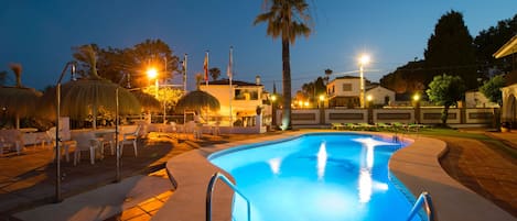 Una piscina al aire libre, sombrillas, tumbonas