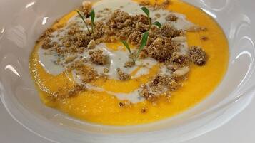 En hvid tallerken med cremet suppe, smuldret topping og et drys.