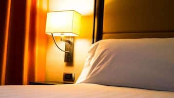 Una habitación de hotel con una cama, una mesita de noche, una lámpara y un cabecero.