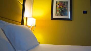 A hotel room with a bed, a nightstand with a lamp, and a framed picture on the wall.
