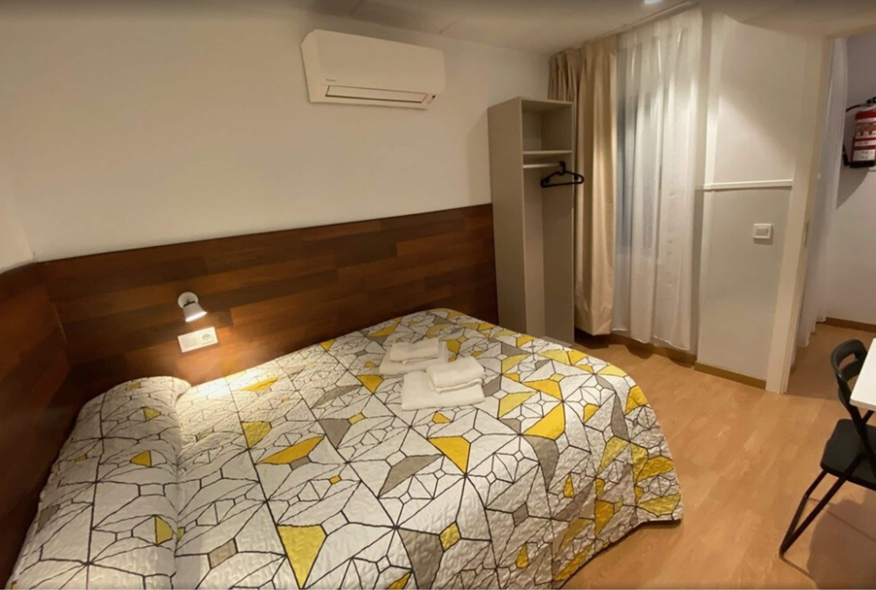 Une chambre d’hôtel avec un lit, une armoire, une chaise et une table.
