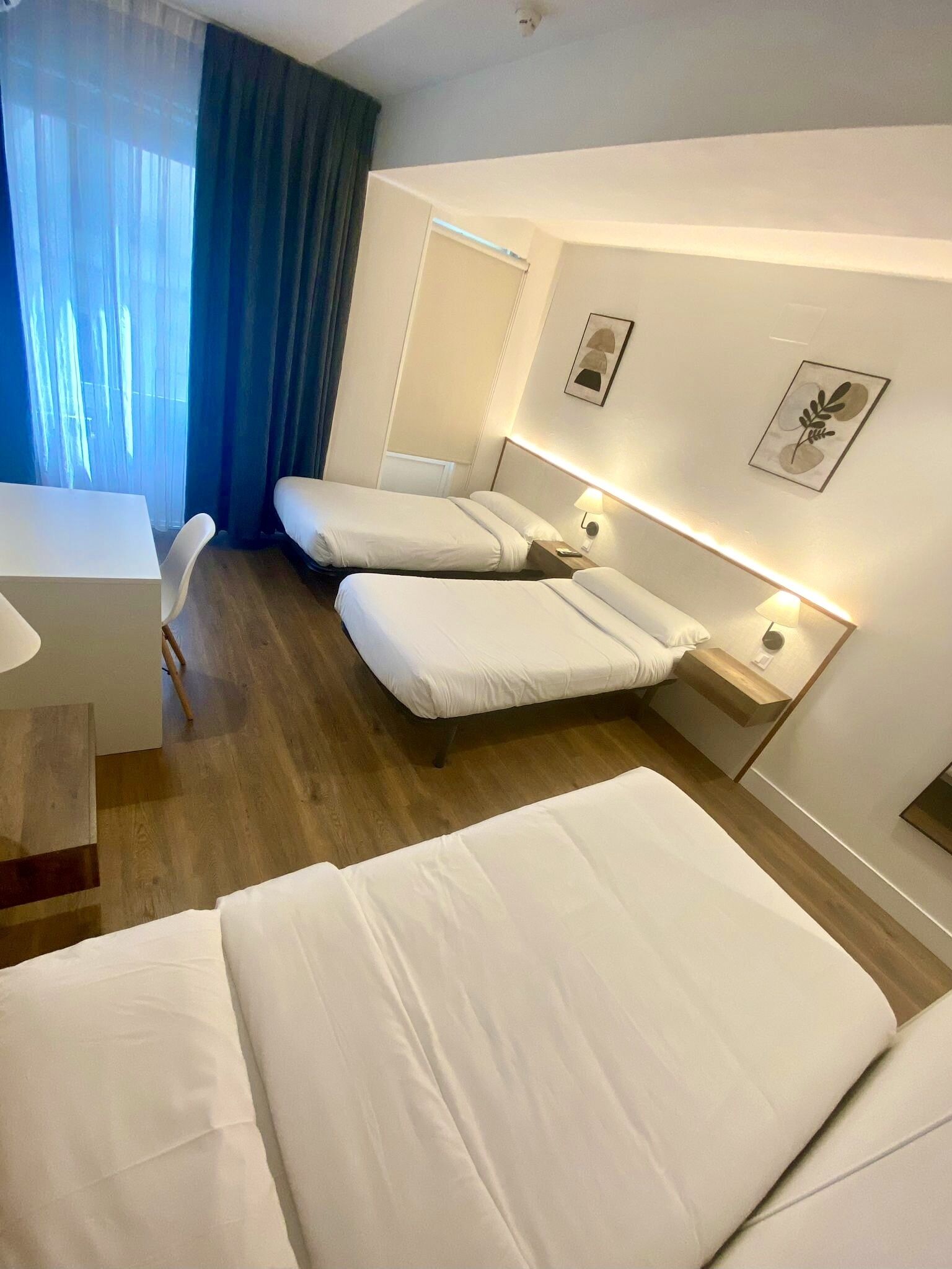 A hotel room with two beds, a desk, and a chair.