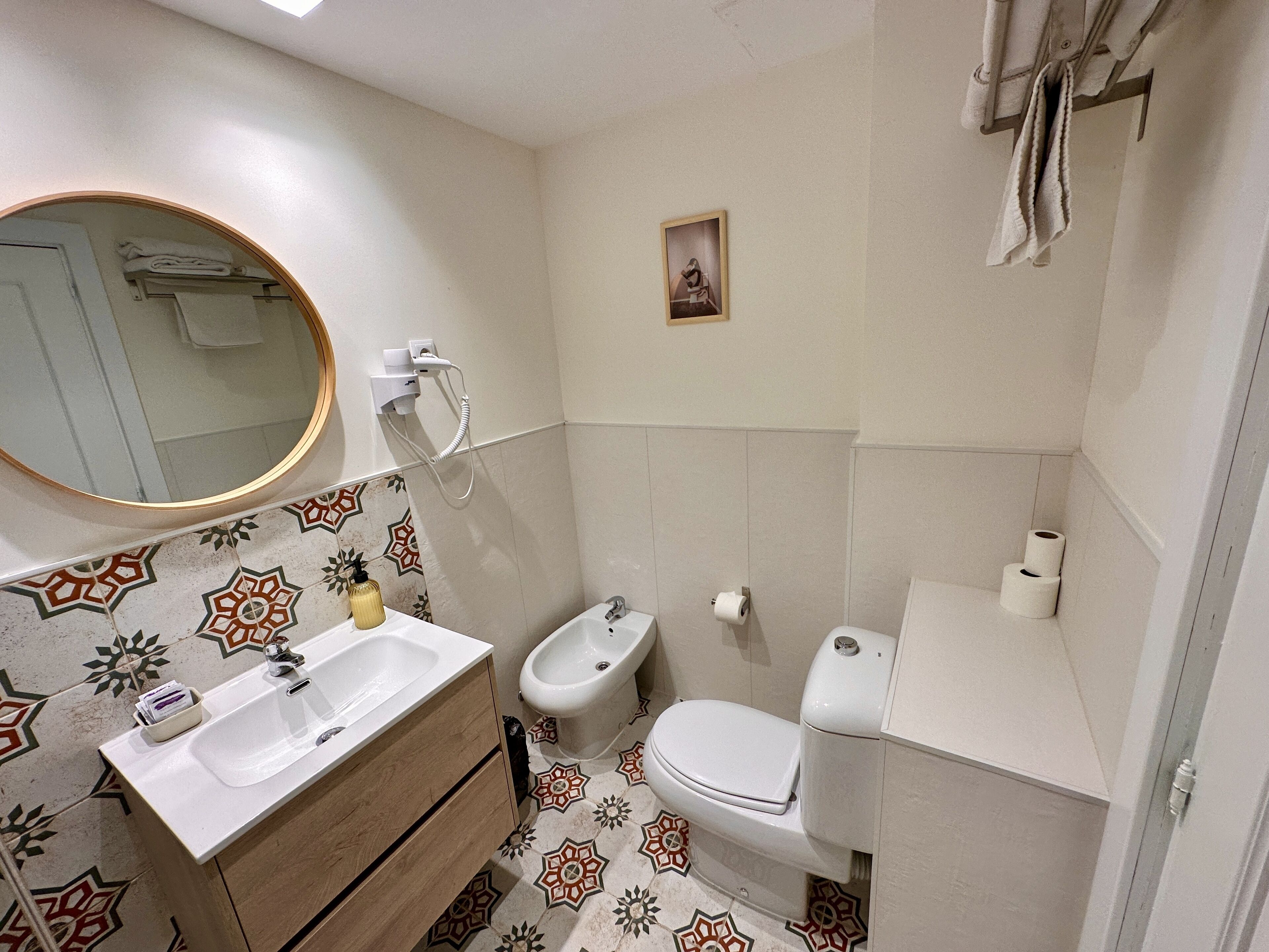 A bathroom with a sink, bidet, toilet, and towel rack.