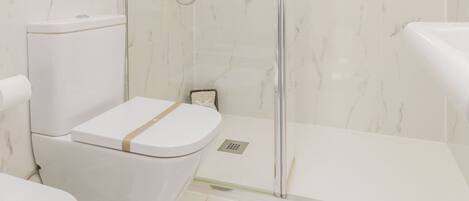 A modern bathroom with a glass-enclosed shower, a toilet, and a bathtub.