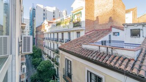 A multi-story building with a mix of modern and traditional architecture, featuring balconies and a tiled roof. - Far Home Gran Vía - Hostel (Madrid)