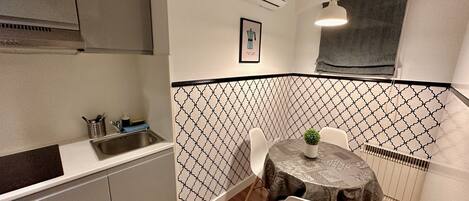 Una cocina compacta con fregadero, estufa y comedor con mesa y sillas.