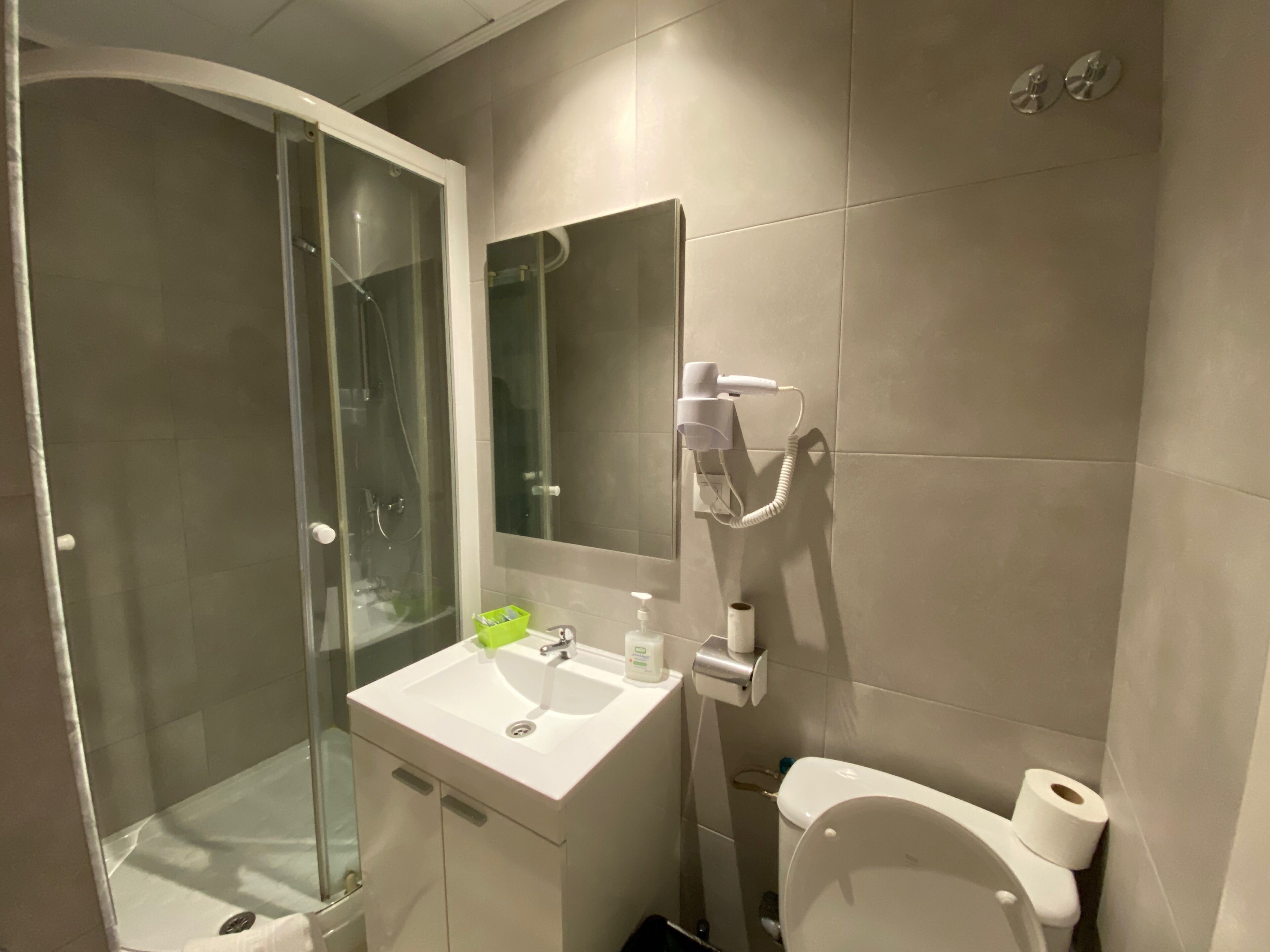 Een badkamer met een douchecabine van glas, een wastafel met spiegel en een toilet.