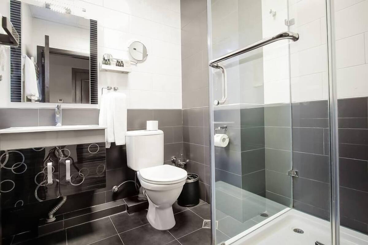 Un baño moderno con cabina de ducha de vidrio, inodoro y lavamanos con espejo.