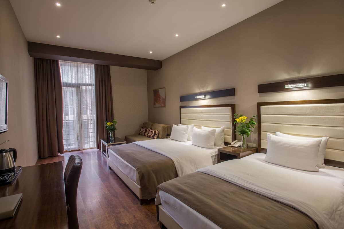 Habitación de hotel con dos camas, un escritorio y una silla.