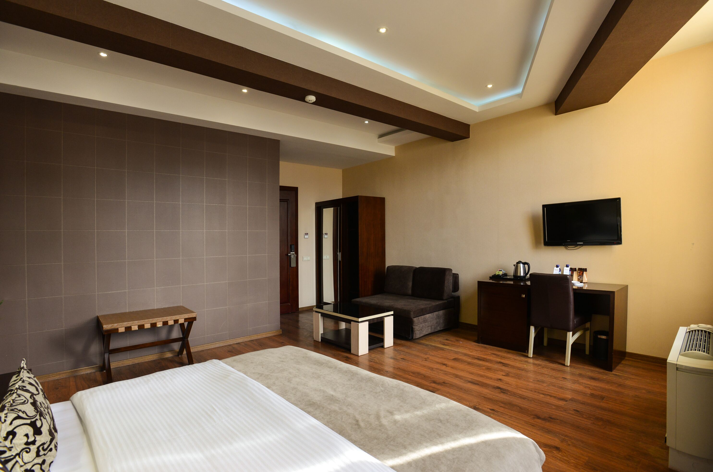 Een hotelkamer met een bed, een bureau, een stoel, een bank en een televisie.