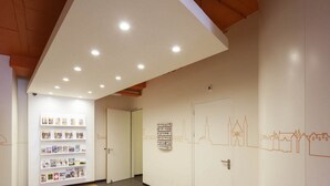 Un pasillo con techo blanco, iluminación empotrada y un mural de paisaje urbano en la pared.