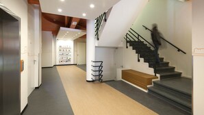 Un interior moderno con una escalera, una zona de recepción y un pasillo con suelo de madera.
