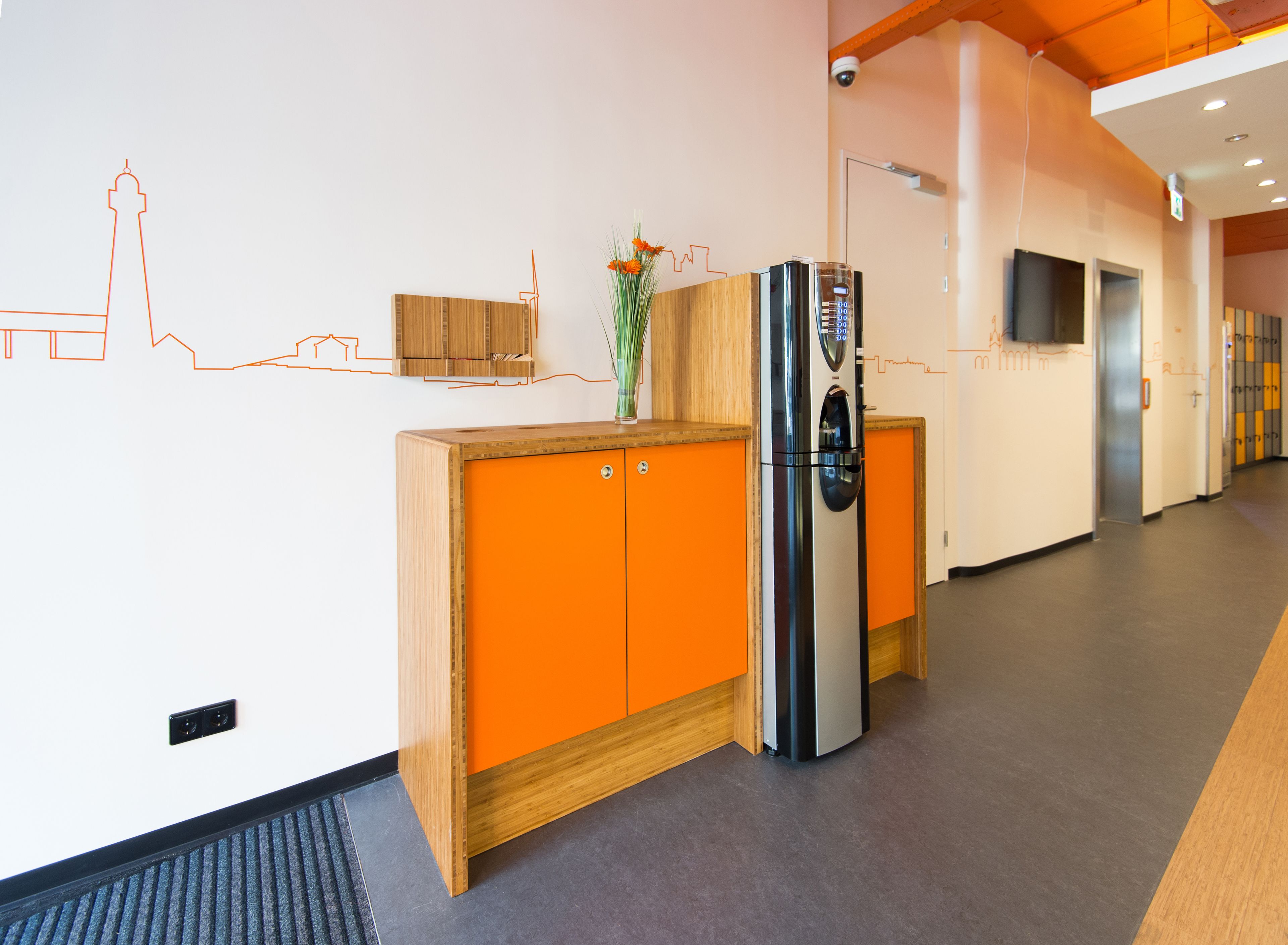 Een moderne keuken met een houten kast, een roestvrijstalen koelkast en een vaas met bloemen op het aanrecht.