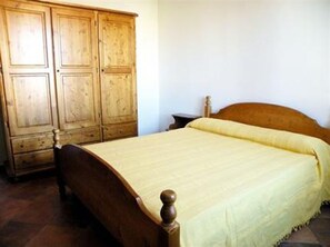 A bedroom with a wooden bed, a wooden wardrobe, and a nightstand. - Sa Tanchitta (Valledoria)