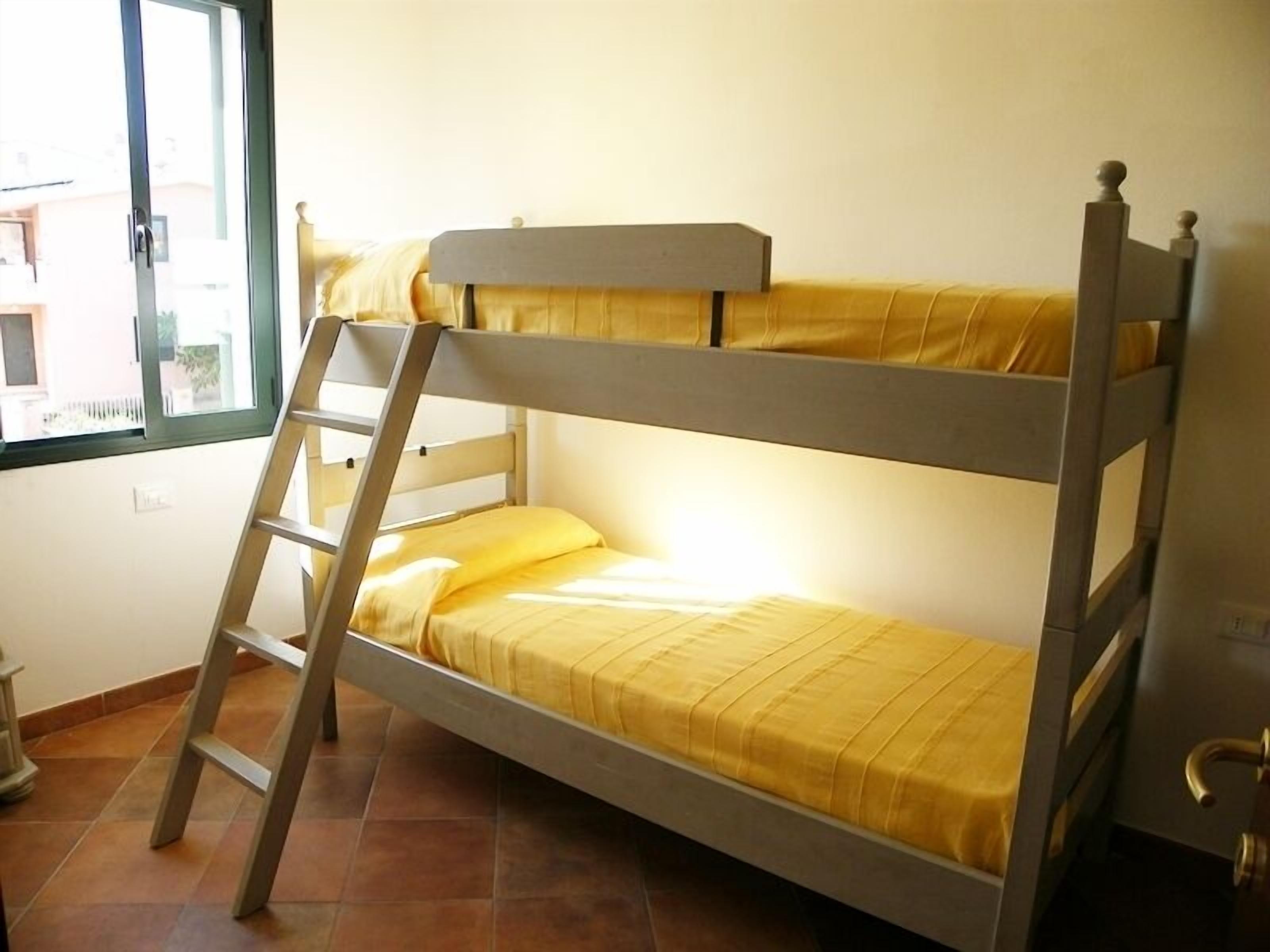 A bunk bed with a ladder, a window with a view, and a door.