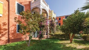 Um edifício com área de jardim, incluindo uma árvore com flores rosa e um gramado bem cuidado.