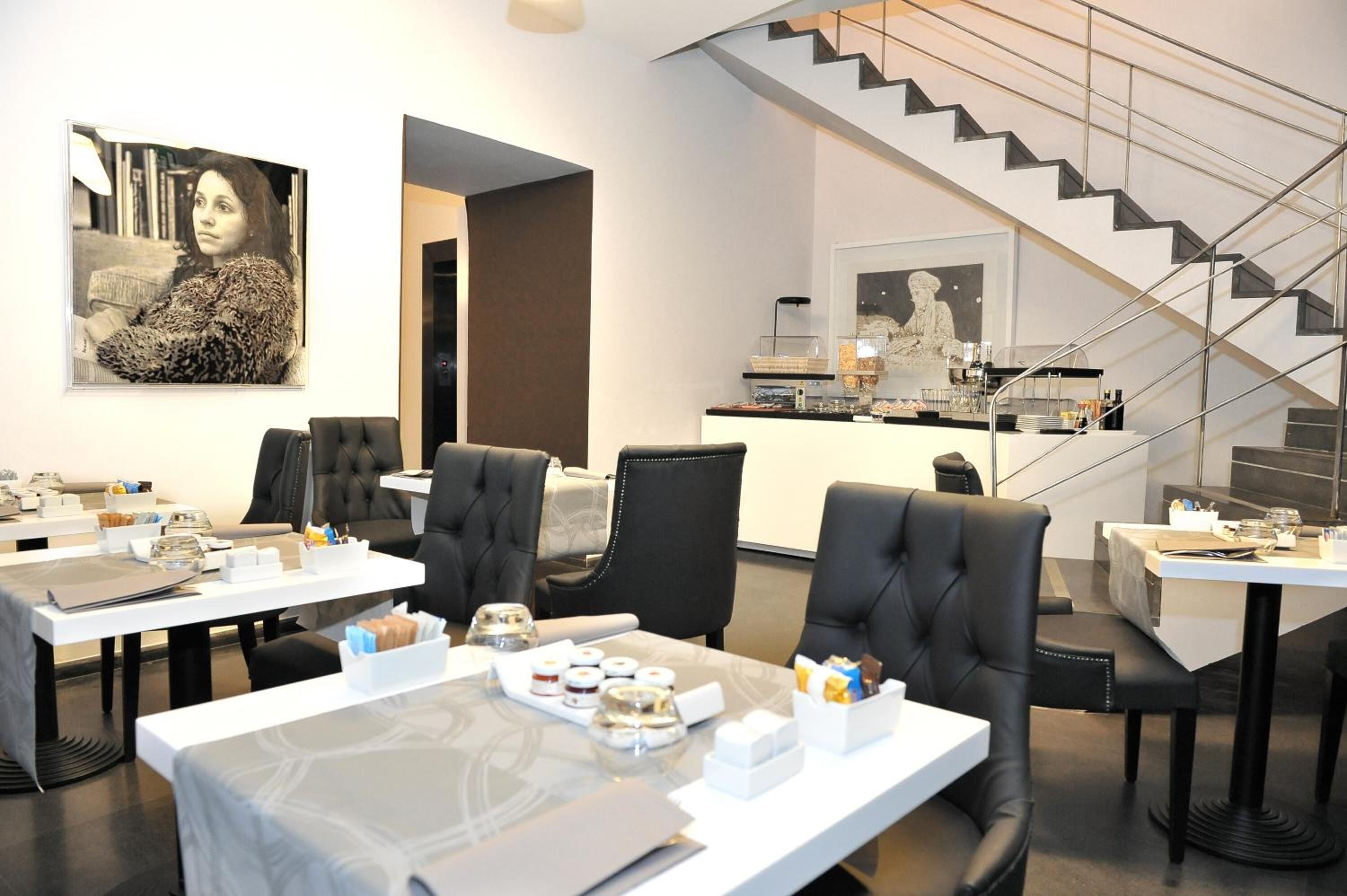 Een moderne hotellobby met een trap, zithoeken en een receptiebalie.