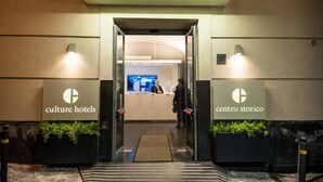 A hotel entrance with a reception desk, a digital screen, and a sign indicating the hotel name. - Culture Hotel Centro Storico (Naples)
