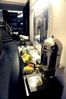 Een buffetopstelling met koffieautomaten en dienbladen met eten.