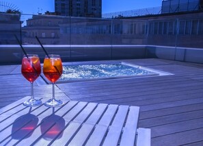 A rooftop terrace with two glasses of red beverages on a wooden table, overlooking a pool. - Culture Hotel Centro Storico (Naples)