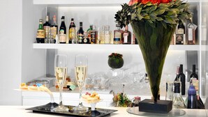 A bar area with shelves of liquor bottles, a large floral centerpiece, and glasses of champagne. - Culture Hotel Centro Storico (Naples)