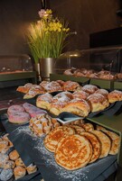 Une vitrine de boulangerie présentant diverses pâtisseries, avec une composition florale en arrière-plan.