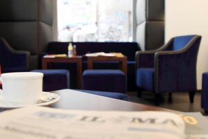 Una zona salotto accogliente con poltrone imbottite blu e un tavolo con una tazza e un piattino bianchi.