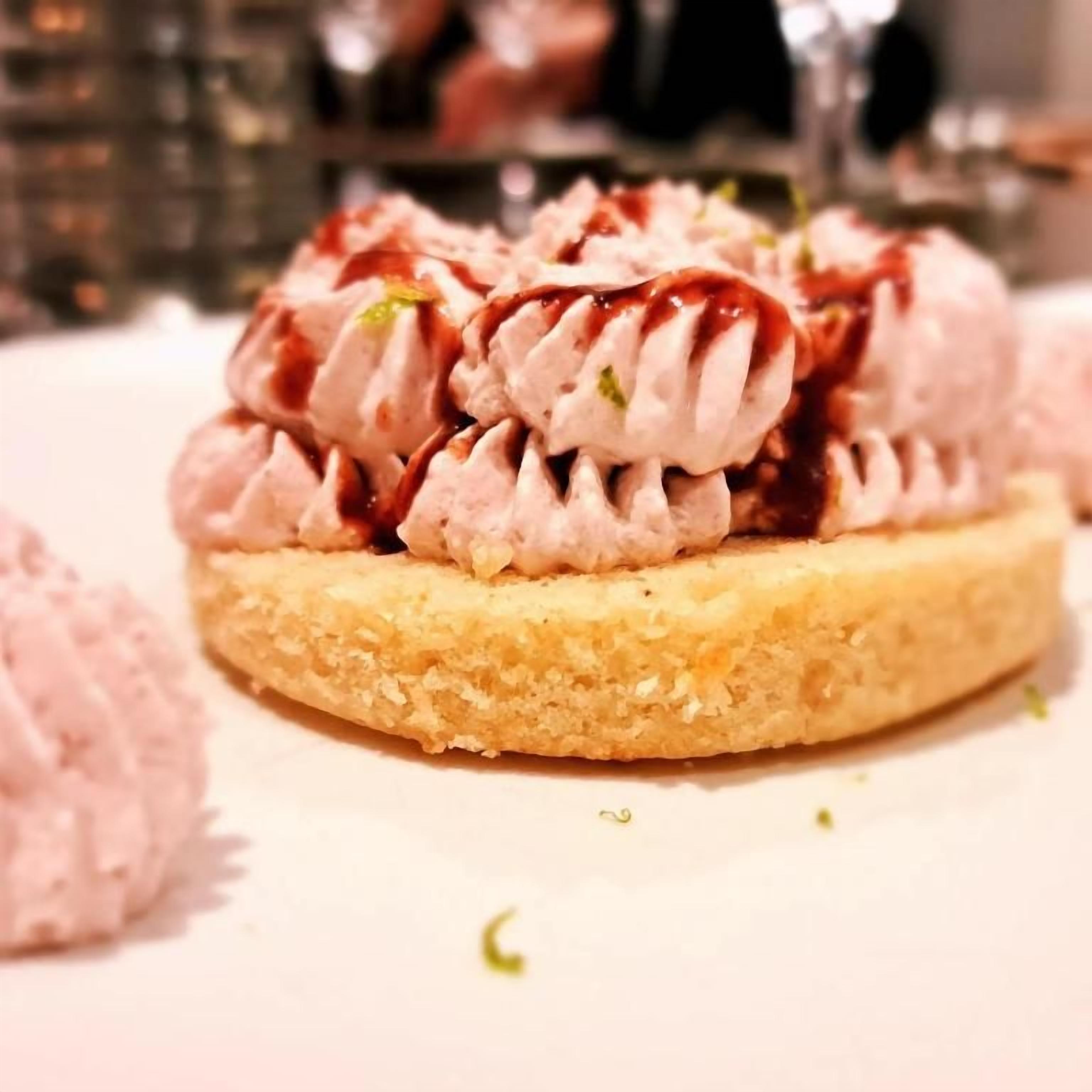 Een dessert met een romige topping en een sausje over een ronde bodem.