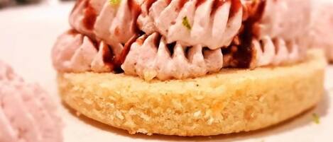 Un postre con cobertura cremosa y un hilo de salsa sobre una base redonda.