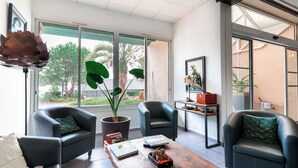 A modern living room with two black leather sofas, a wooden coffee table, and a large potted plant.