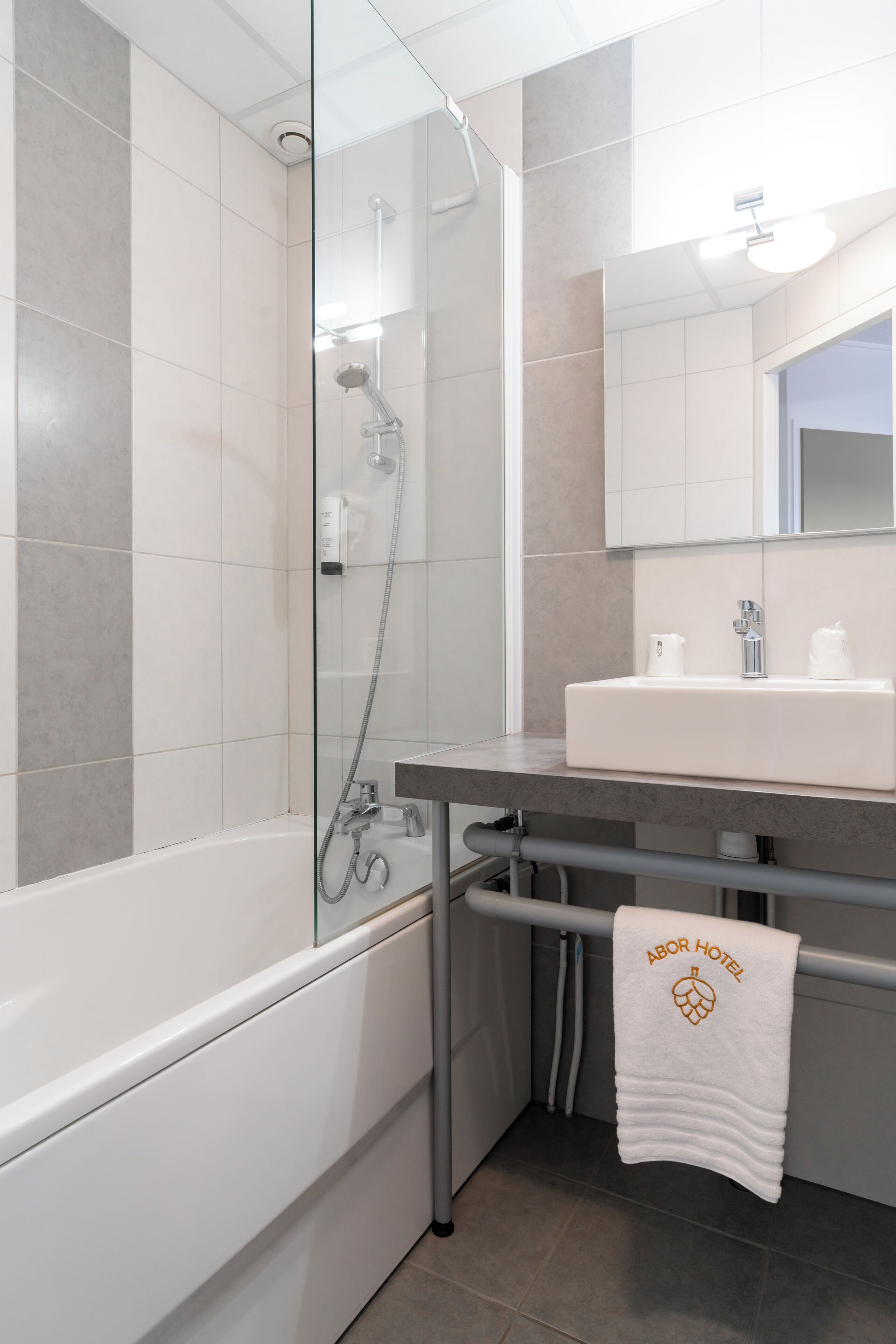 A modern bathroom with a glass-enclosed shower, a white sink, and a towel rack with a towel.