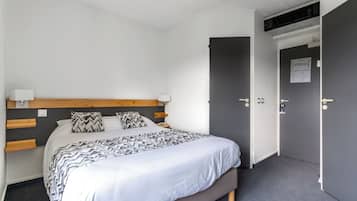 A bedroom with a bed, bedside lamps, a headboard, and a door.