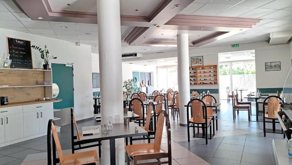 Un restaurante con varias mesas y sillas, una barra con un menú, y vistas al exterior.