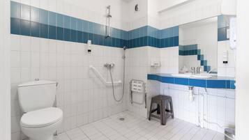 Een badkamer met toilet, douche, wastafel en spiegel.