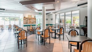 A spacious indoor dining area with multiple tables and chairs, large windows, and a shoe display.
