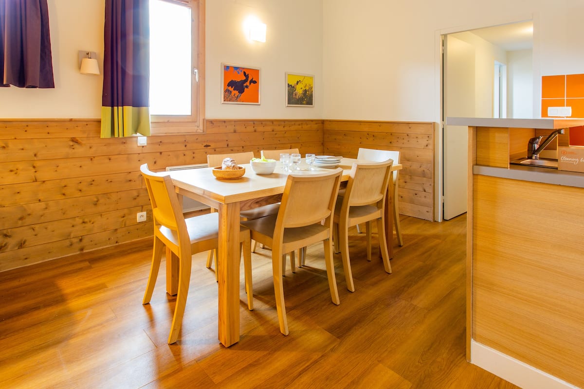 Un comedor con mesa y sillas de madera, una estación de buffet y paneles de madera en las paredes.