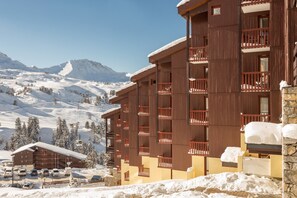 A multi-story hotel with balconies, set against a snowy mountain backdrop. - Résidence Pierre & Vacances Les Gémeaux (La Plagne-Tarentaise)