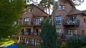 A multi-story brick building with balconies, a swimming pool, and outdoor seating. - Australis Paradise (Carilo)
