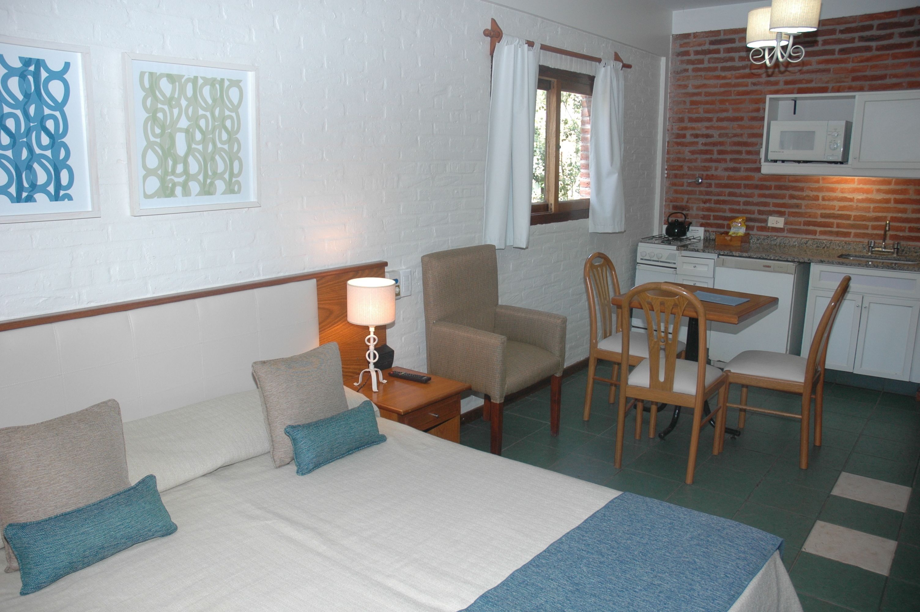 Habitació d'hotel amb un llit, escriptori, cadira, microones i finestra amb cortines.