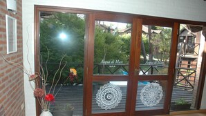A spa entrance with a wooden door, decorative glass panels, and a white vase with dried flowers on the left. - Australis Paradise (Carilo)